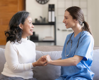 caregiver and senior woman holding hands