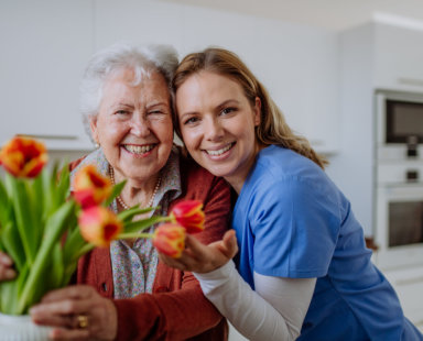 senior woman and a caregiver touching flowers