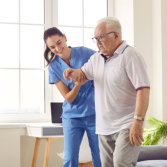 caregiver helps a senior man to walk