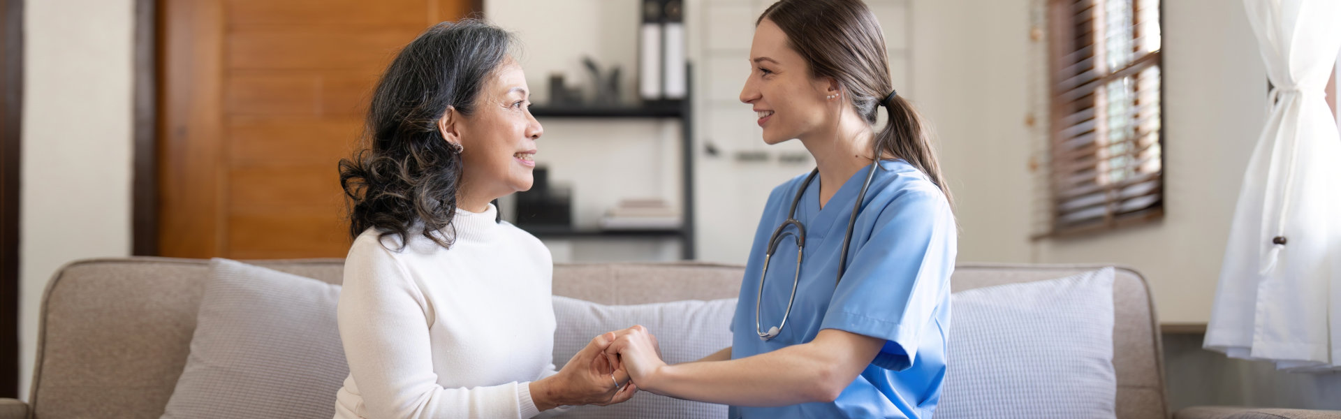 nurse and senior woman holding each other's hands